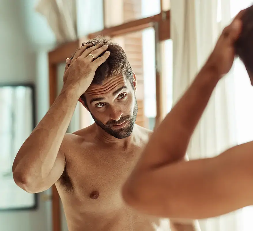 Man feeling his hair looking in the mirror